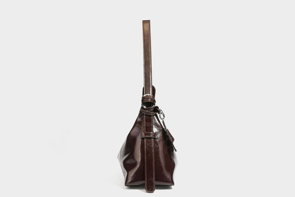 Glossy dark brown hobo shoulder bag with slim strap, front zip pocket, stud detail, and detachable leopard-print heart charm
