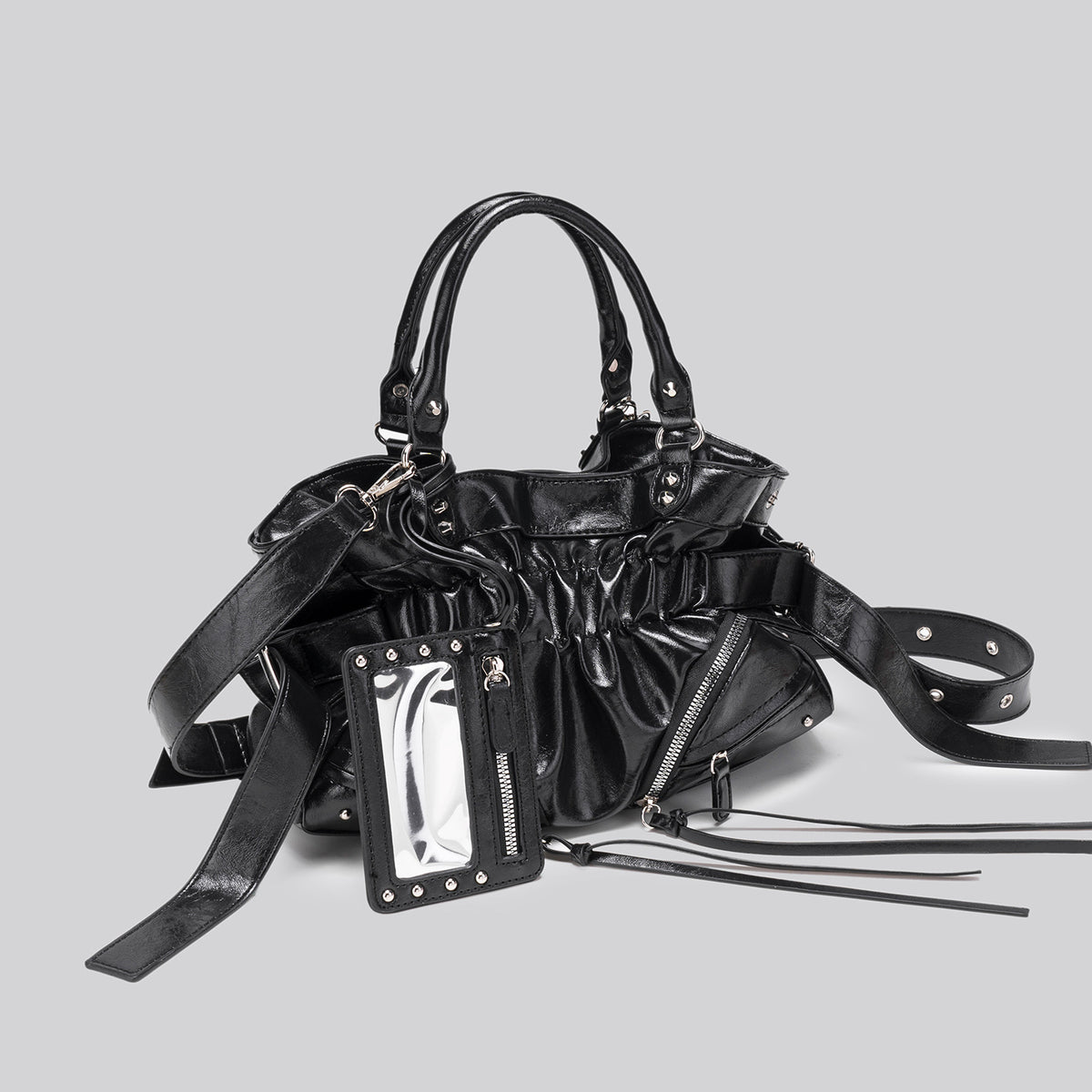 Black glossy ruched convertible tote bag with silver-tone rivets, detachable wide shoulder strap, external zip pouch, and