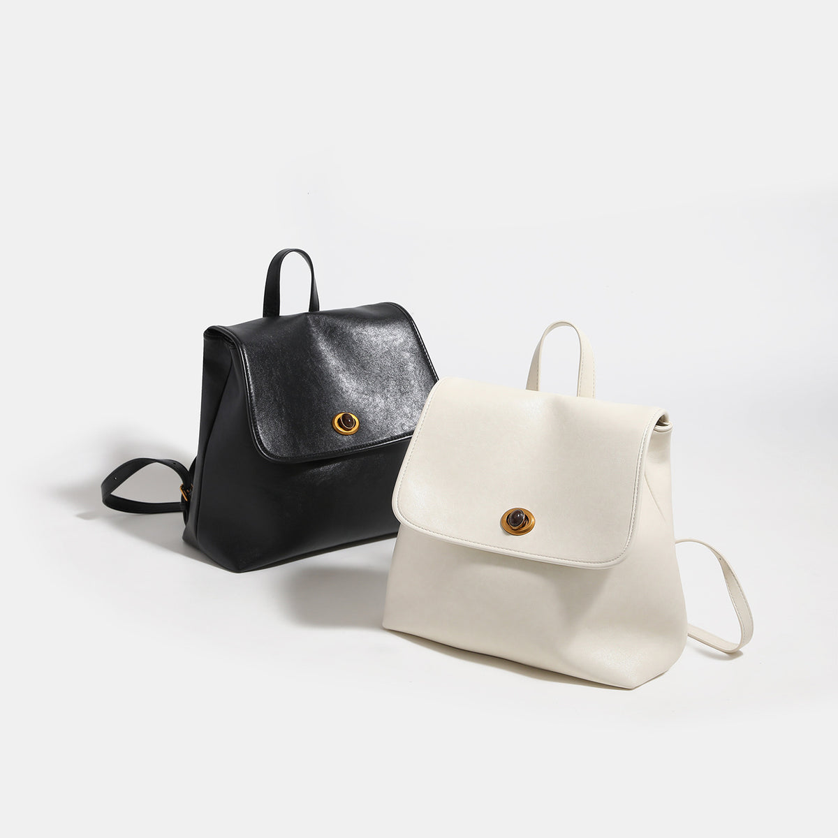 Structured flap backpack purse with round gold-tone clasp, top handle, and twin shoulder straps, detail view 2