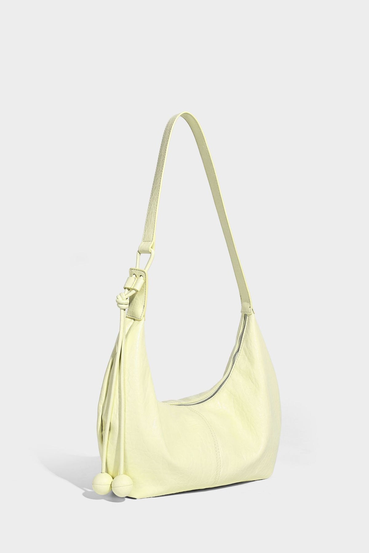 Slouchy crescent half-moon shoulder bag in pink pebbled textured finish with floral charm and knotted side detail, detail