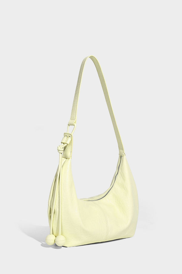 Slouchy crescent half-moon shoulder bag in pink pebbled textured finish with floral charm and knotted side detail, detail
