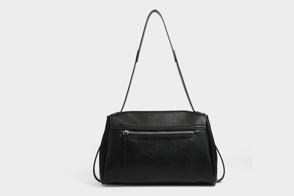 Strukturierte rechteckige dunkelbraune Schultertasche in Lederoptik mit Klappe, mehrlagigem Detail auf der Vorderseite und langem verstellbarem Riemen, Detailansicht