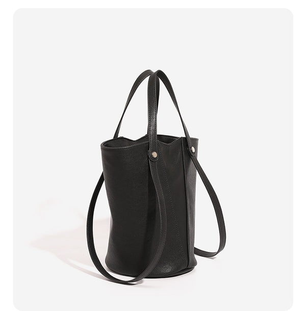Structured black leather-look bucket tote bag with slim shoulder straps, silver-tone stud hardware, and tapered body, detail