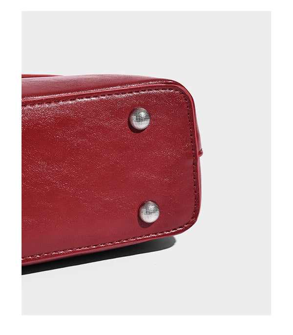 Structured glossy leather-look shoulder bag with wraparound belt straps, silver-tone hardware, and dangling star charm