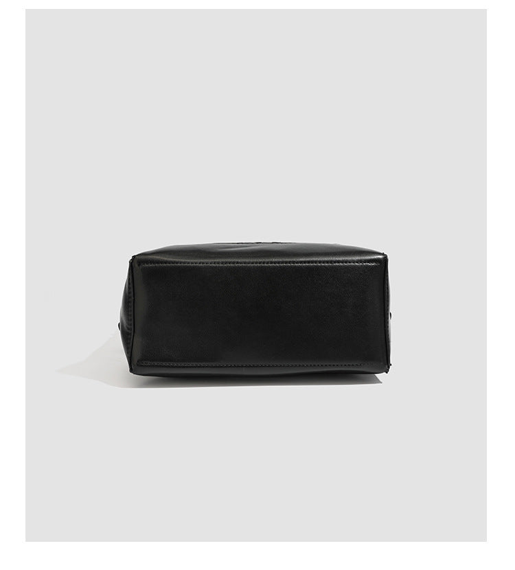 Large black bucket shoulder bag with diamond woven leather-look front panel, smooth side panels, magnetic snap closure, and
