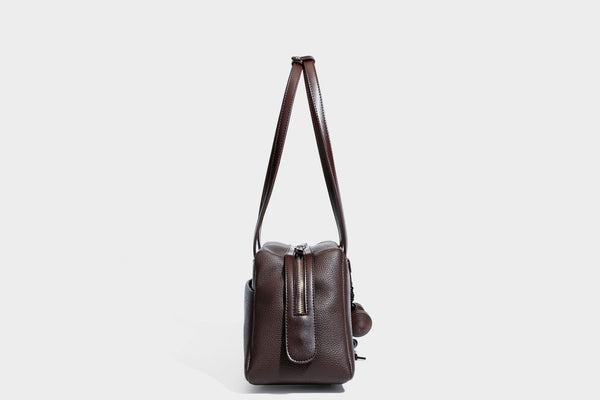 Structured trapezoid shoulder bag in dark brown pebbled leather-look finish with slim double straps, top zip closure, side