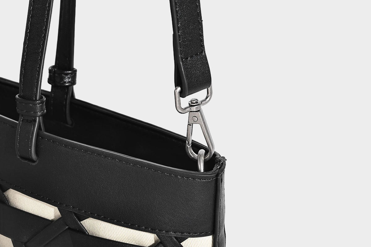 Structured woven lattice cutout tote bag with smooth leather-look trim, dual shoulder straps, and silver-tone hardware