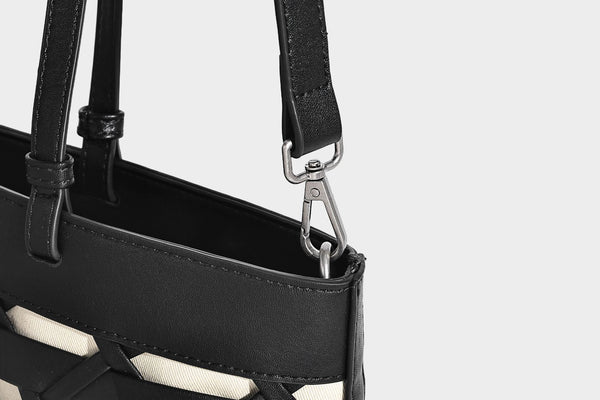 Structured woven lattice cutout tote bag with smooth leather-look trim, dual shoulder straps, and silver-tone hardware