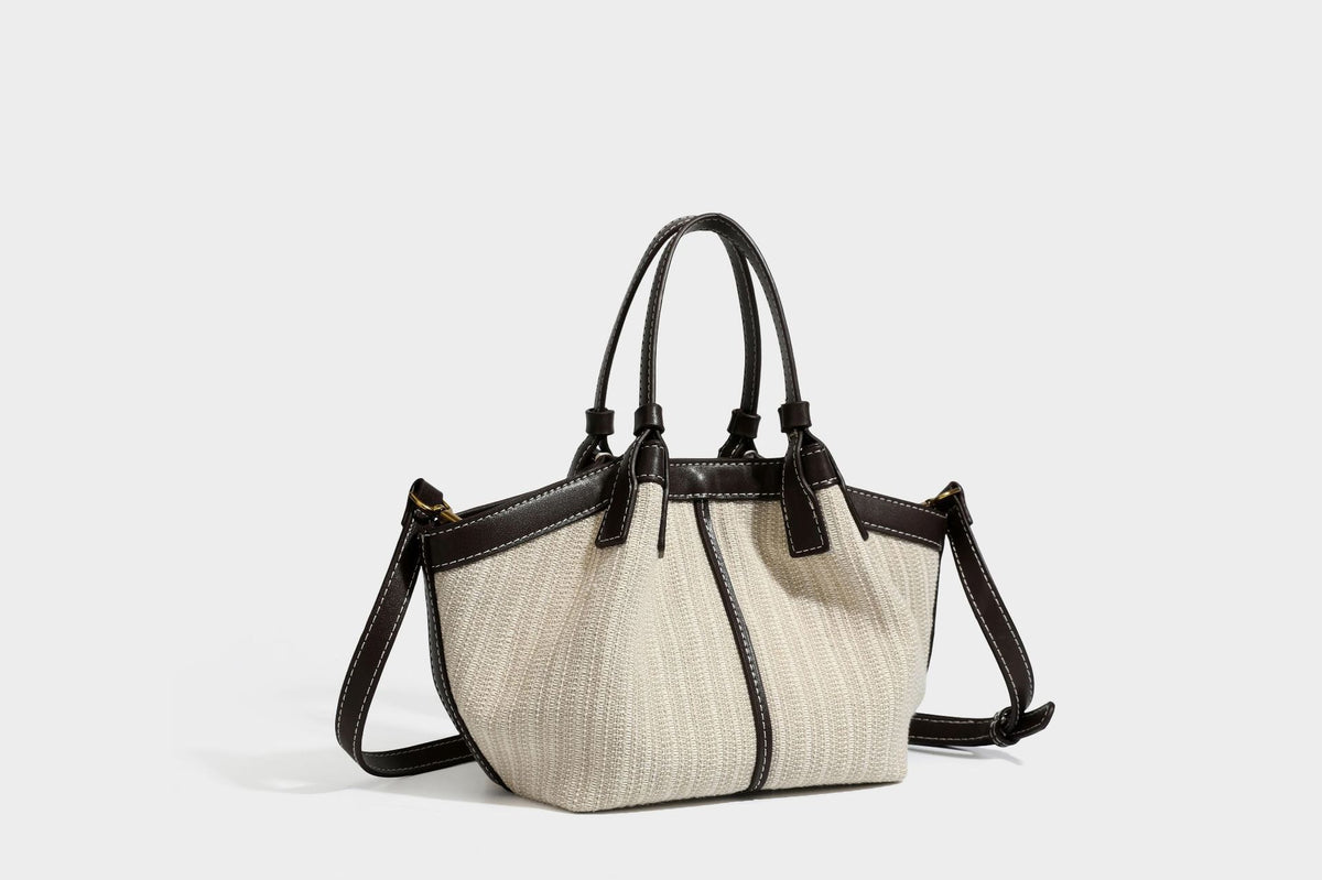 Cremefarbene geflochtene Tote-Bag mit dunkelbraunen Besätzen in Lederoptik, kontrastierenden weißen Nähten, zwei oberen Henkeln und abnehmbarem Schulter
