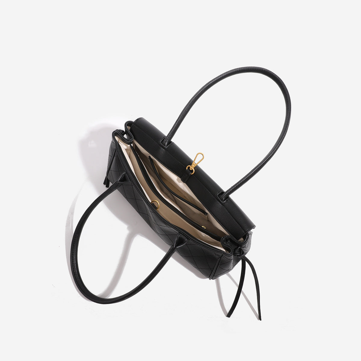 Structured black baguette bag with diamond-quilted front panel, gold-tone turn-lock flap closure, and dual looped top