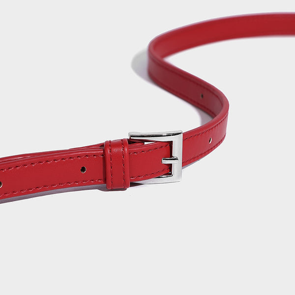 Small structured shell top-handle bag in red with heart charm and braided cord detail, smooth leather-look finish, detail