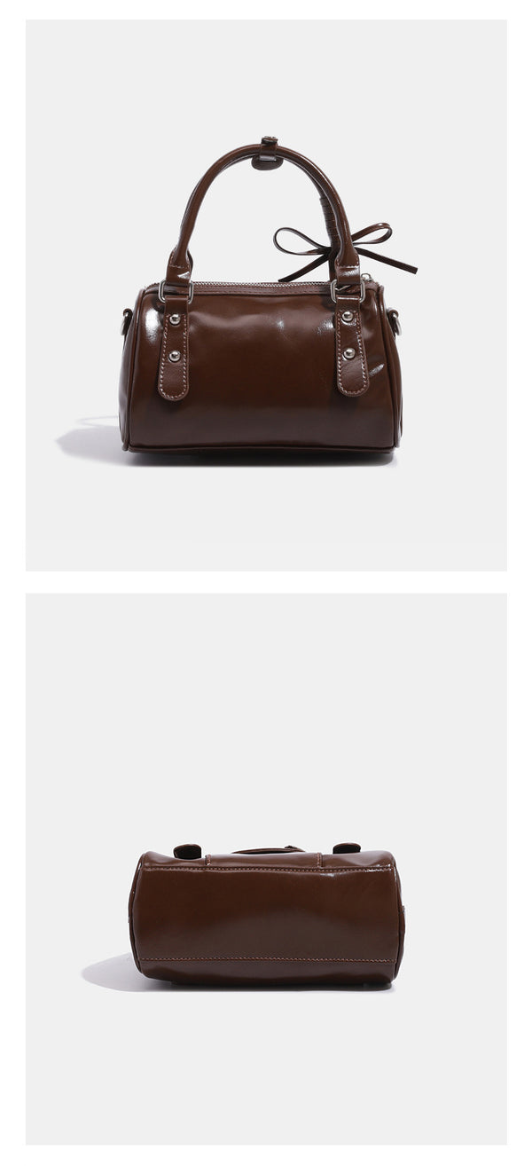 Kleine, formstabile Glanzledertasche mit zwei Henkeln, vorderer Klappentasche, herzförmigem Charm-Verschluss und silberfarbenem