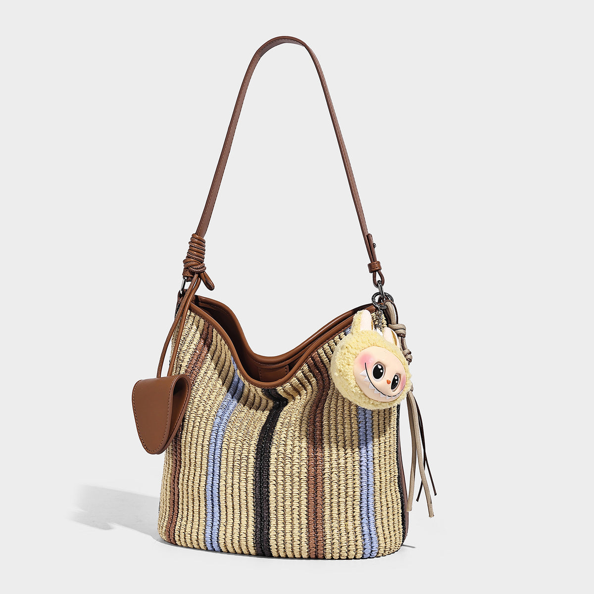 Striped woven straw-style shoulder bag with tan leather-look trim and long adjustable strap, front view