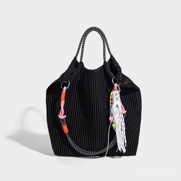 Slouchy pinstripe tote bag with braided rope handles, metal ring hardware, and colorful knotted rope charm, detail view 6