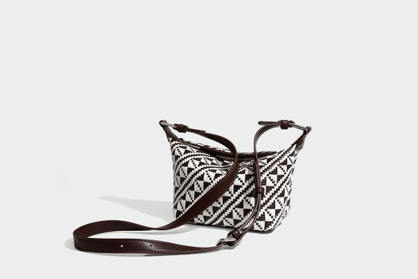 Kleine schwarz-weiße Schultertasche mit gewebtem geometrischem Muster, glatter dunkelbrauner Besatz aus Lederoptik, geknotetem verstellbarem Riemen und seitlichem