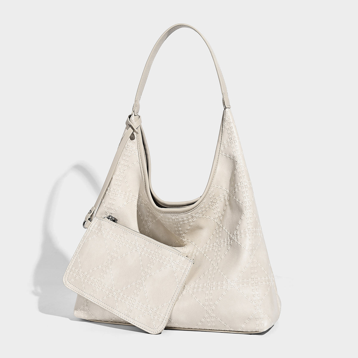 Slouchy hobo shoulder bag in ivory with embossed leather-look finish, single shoulder strap, and detachable zip pouch with