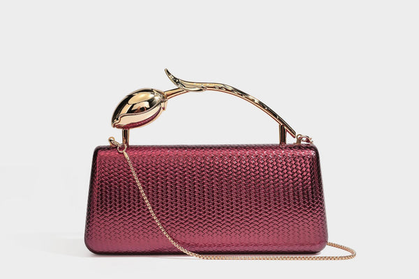 Structured rectangular metallic woven clutch bag with sculptural gold-tone leaf top handle and detachable chain strap, detail