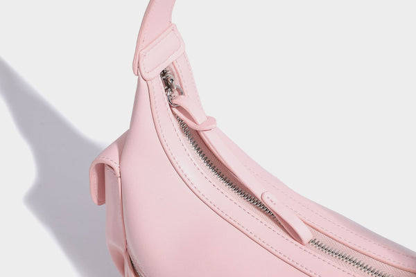 Smooth leather-look crescent shoulder bag with front zip pocket, side flap pockets, adjustable strap, and silver-tone, detail