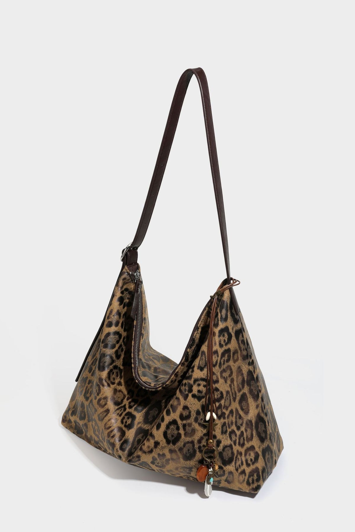 Slouchy leopard print hobo shoulder bag with glossy coated finish, top zipper closure, dark brown trim, and dangling charm