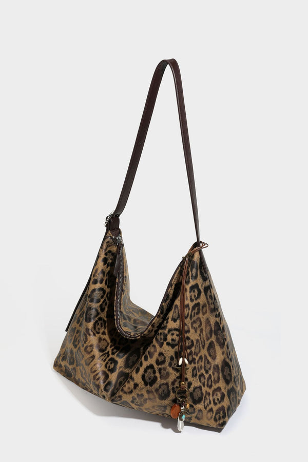 Slouchy leopard print hobo shoulder bag with glossy coated finish, top zipper closure, dark brown trim, and dangling charm