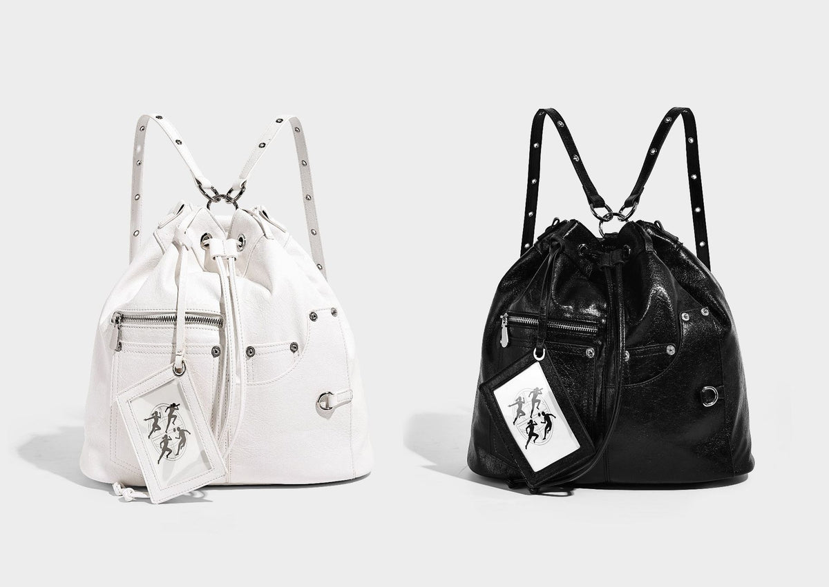Glossy black convertible bucket backpack with silver grommet-studded straps, drawstring cinch closure, and front zip pocket