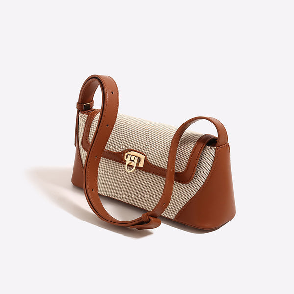 Structured trapezoid flap shoulder bag with canvas-textured body, smooth contrast trim, and gold-tone turn-lock clasp, detail