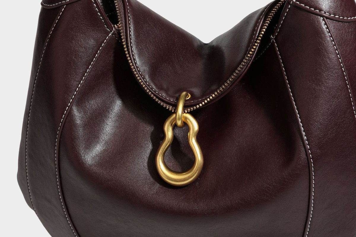 Lässige halbmondförmige Hobo-Schultertasche in Dunkelbraun mit goldfarbenem Ring und Kettenglied-Beschlägen sowie Reißverschluss oben, Detailansicht