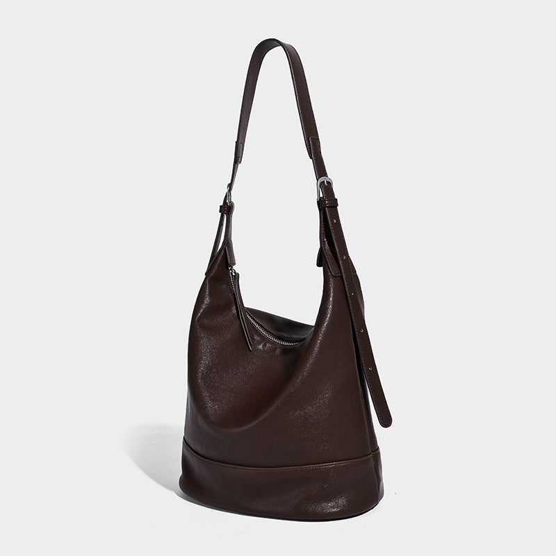 Slouchy bucket hobo shoulder bag in dark brown with glossy leather-look finish, top zip closure, and long adjustable, front