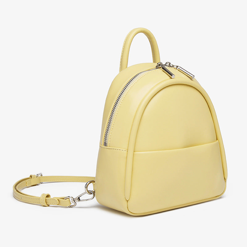 Kleine kuppelförmige Mini-Rucksackhandtasche in Pastellgelb mit glatter Oberfläche in Lederoptik, bogenförmigem Reißverschluss oben und silberfarbenen Details