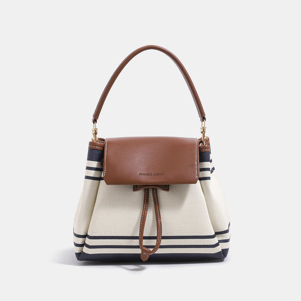 Cremefarbene Canvas-Beuteltasche mit marineblauen horizontalen Streifen, cognacfarbenem Kunstleder-Lappen und -Besatz, goldfarbenen Metalldetails und wandelbarer Trageweise