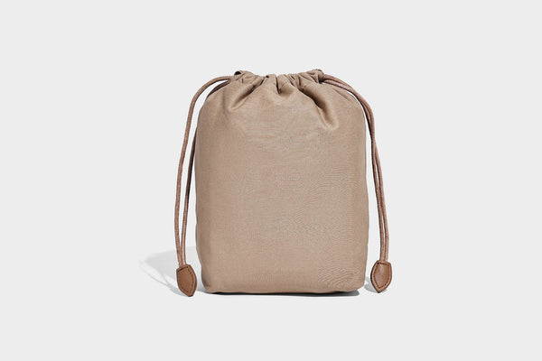 Small woven lattice bucket bag in tan and cream leather-look strips with drawstring top and detachable crossbody strap