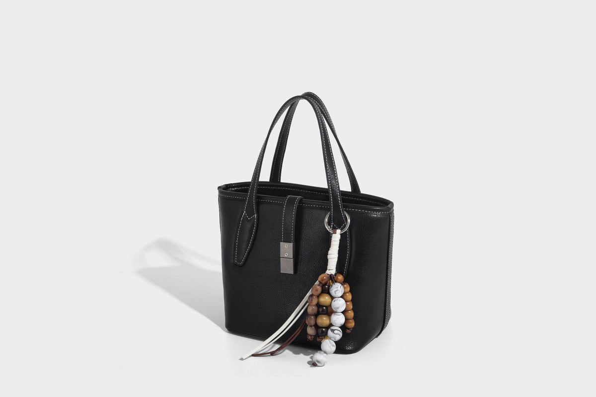 Compact structured bucket tote bag with pebbled textured finish, dual top handles, silver-tone lock hardware, and detachable