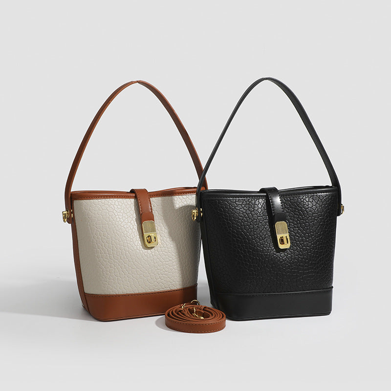Formstabile zweifarbige Bucket Bag aus genarbtem Material mit goldfarbenem Drehverschluss und cognacfarbenem Besatz in Lederoptik, Detailansicht 2