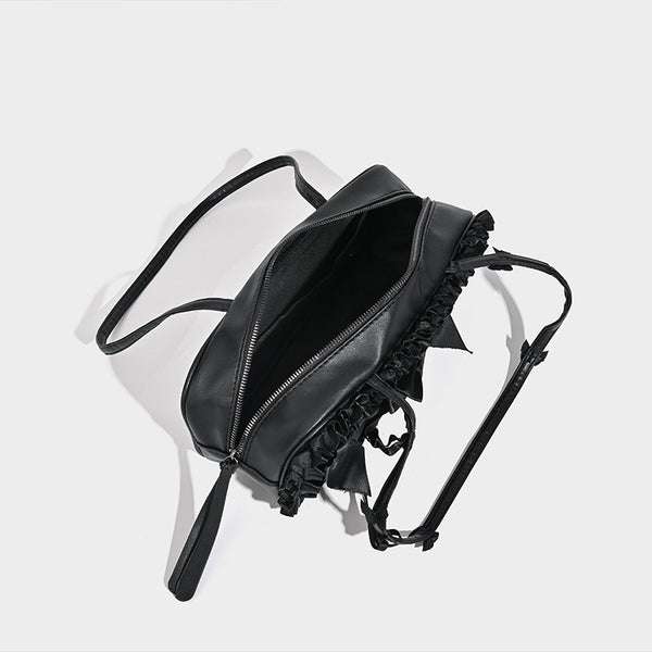 Black leather-look structured tote bag with gathered ruffle trim, ribbon bow accents, top zip closure, and attached card