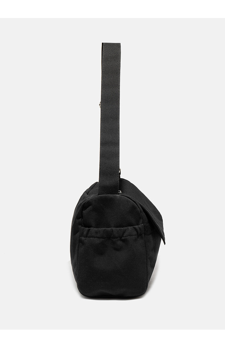Große schwarze Messenger-Tasche aus mattem Canvas mit Überschlag vorn, Reißverschluss oben, elastischen Seitentaschen und verstellbarem silberfarbenem