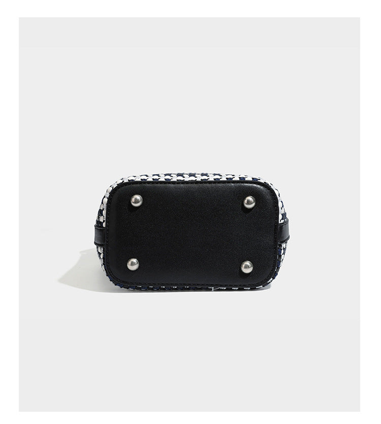 Small structured woven checker bucket bag with braided top handle, drawstring closure, and silver-tone hardware in black