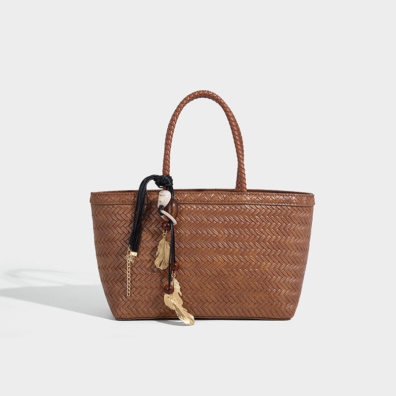Structured chevron woven leather-look tote bag with braided top handles, gold feather charm, and adjustable shoulder strap