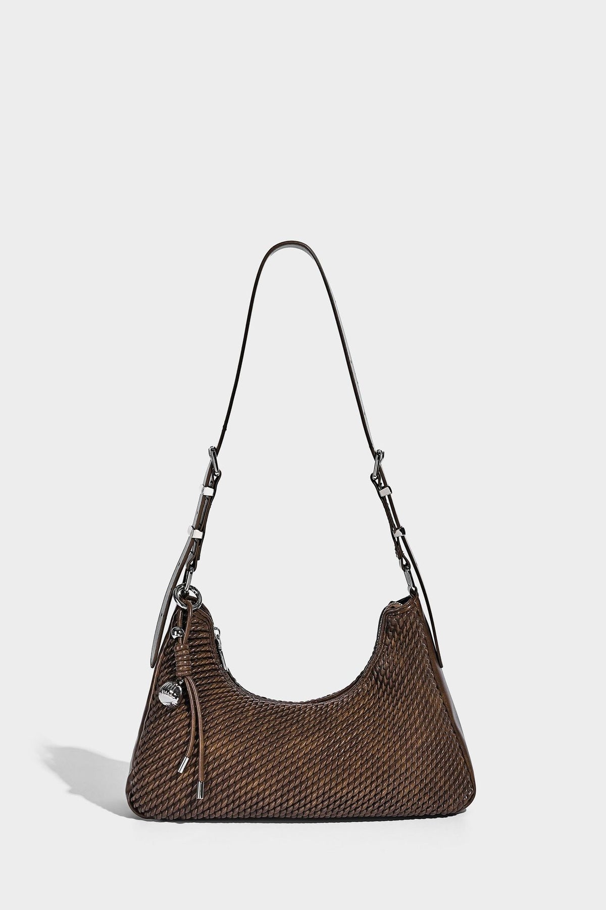 Woven crescent hobo shoulder bag with smooth side panels, zip-top closure, silver-tone charm hardware, and adjustable, detail