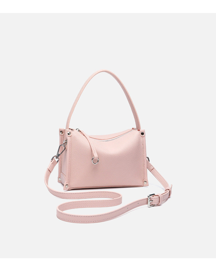 Small structured pebbled-finish convertible bag with silver corner studs, zip top, and detachable shoulder strap, detail view
