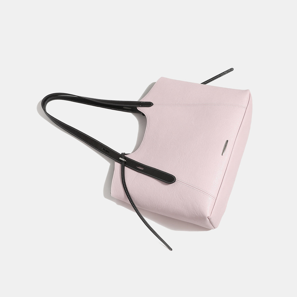 Structured trapezoidal tote bag with smooth leather-look finish, long black contrast shoulder straps, and dangling strap