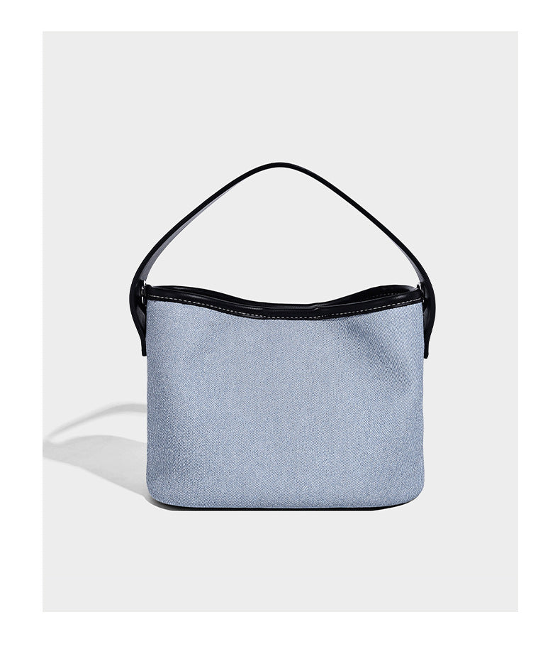 Small denim-look bucket bag with black leather-look trim, pink tulip flower charm, and adjustable crossbody strap, detail