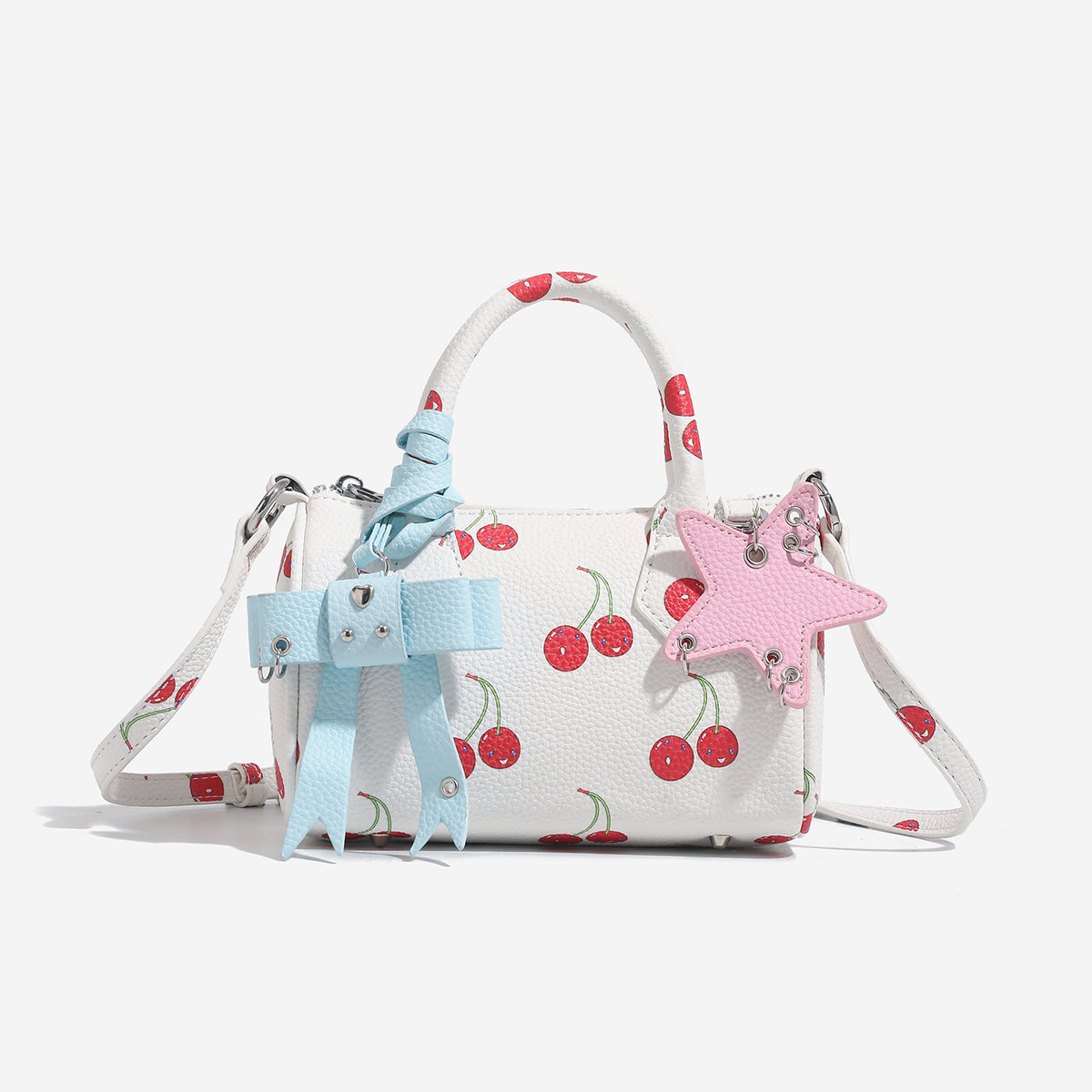 Weiße Mini-Boston-Handtasche mit genarbter Oberfläche und Blumen- oder Kirschprint, pastellblauem Schleifenanhänger, rosafarbenem Sternanhänger und zwei oberen Henkeln