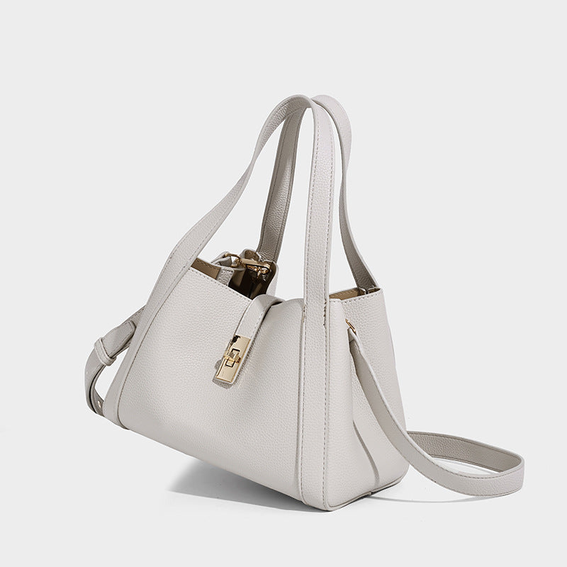Structured trapezoid tote bag in taupe pebbled leather-look finish with gold-tone turn-lock hardware, dual top handles, and