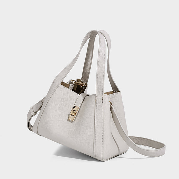 Structured trapezoid tote bag in taupe pebbled leather-look finish with gold-tone turn-lock hardware, dual top handles, and