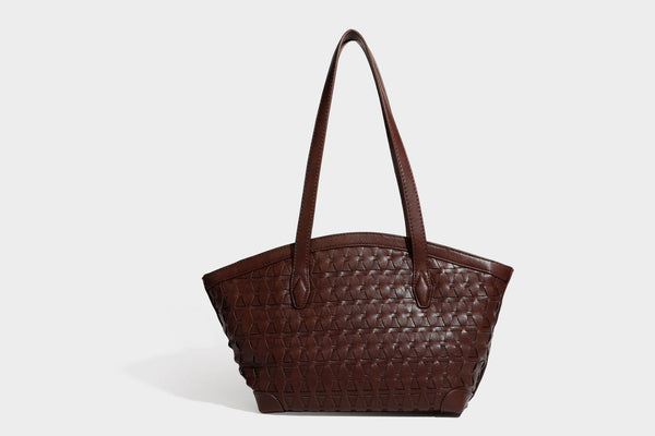 Large leather-look tote bag with geometric woven emboss, double shoulder straps, and round woven cord charm in brown, detail
