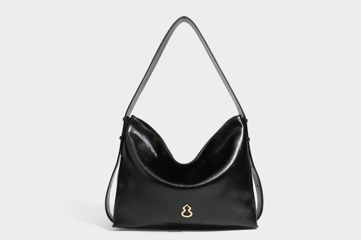 Lässig fallende Hobo-Schultertasche mit offenem Oberteil aus glänzender, karamellbrauner Lederoptik, mit Logo-Beschlägen in Goldoptik und langem, verstellbarem