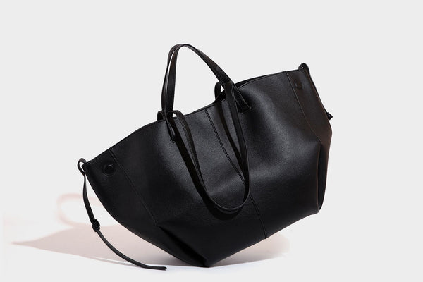Große, formstabile trapezförmige Tote-Bag aus braunem Lederimitat mit genarbter Oberfläche, zwei Tragegriffen und seitlichen Bindebändern, Detail