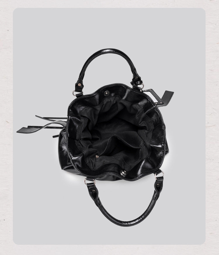 Black glossy ruched convertible tote bag with silver-tone rivets, detachable wide shoulder strap, external zip pouch, and