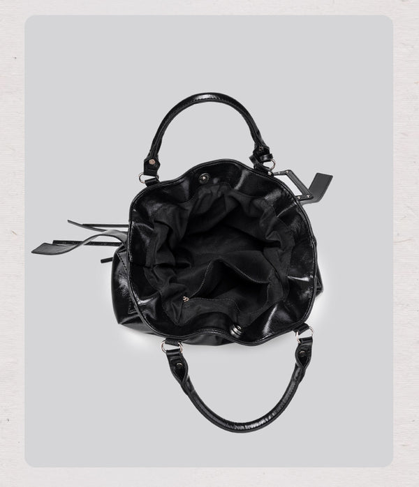 Black glossy ruched convertible tote bag with silver-tone rivets, detachable wide shoulder strap, external zip pouch, and