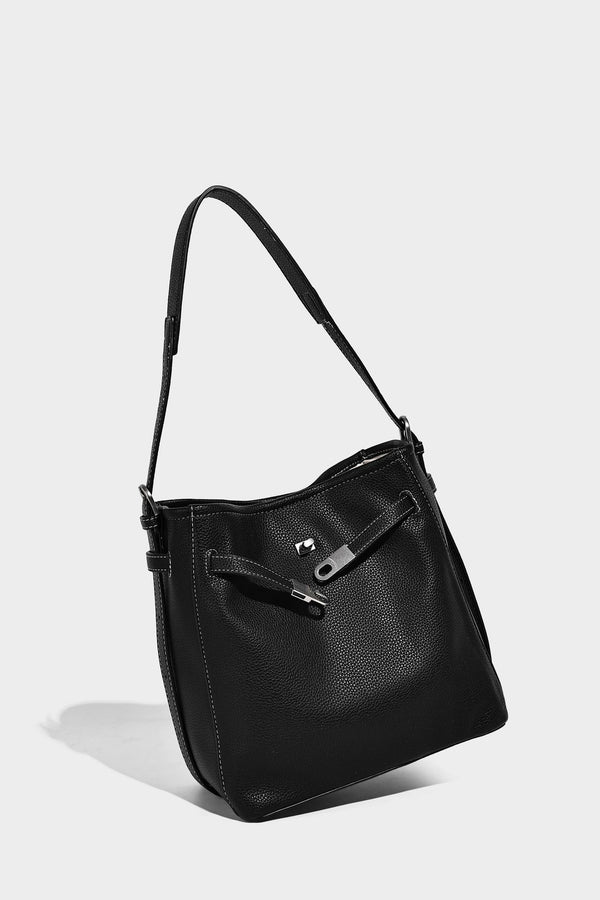 Soft-structured pebbled bucket shoulder bag with front turn-lock strap detail, adjustable strap, and hanging floral tassel